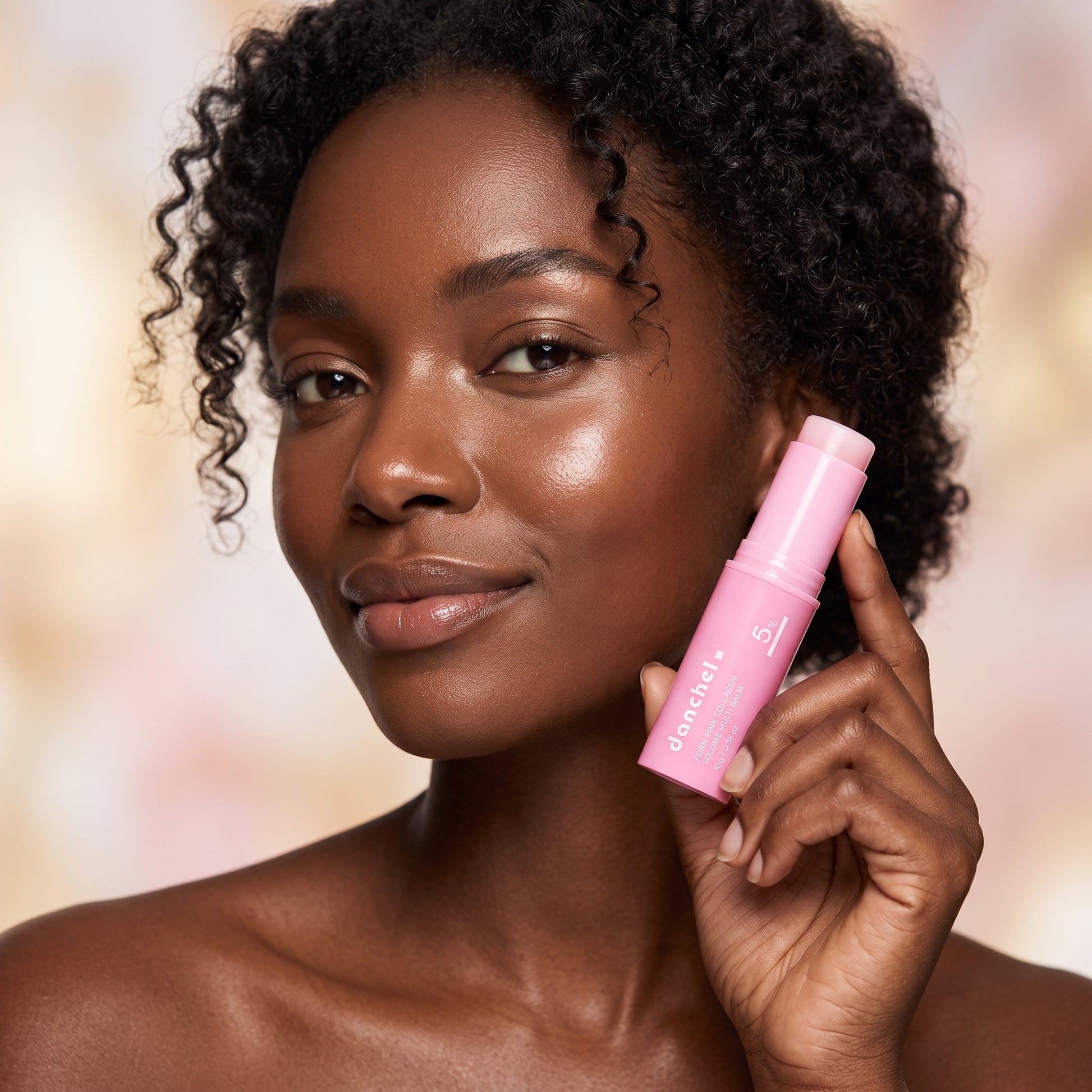 Woman with luminous dewy glowing skin holding danchel glow balm stick